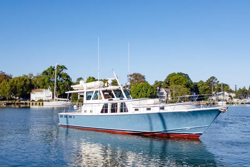 Slide: The Image of 2001 Dettling 51 yacht on calm water, surrounded by lush greenery and waterfront homes. - 4