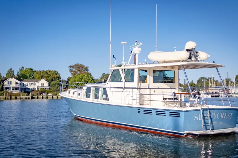 Slide: The Image of Luxury Dettling 51 yacht from 2001 on serene water, with houses in the background. - 6