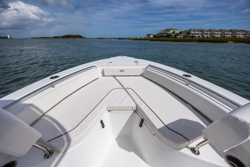 Slide: The Image of Bow view of 2020 Sea Hunt Ultra 225 boat on calm water, with scenic shoreline. - 10