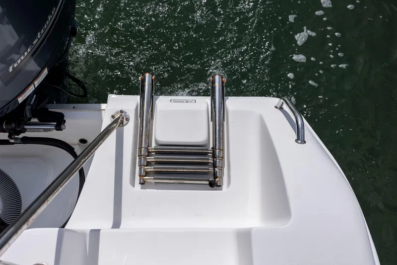 Slide: The Image of 2020 Sea Hunt Ultra 225 boat with folded swim ladder and outboard motor on water. - 20