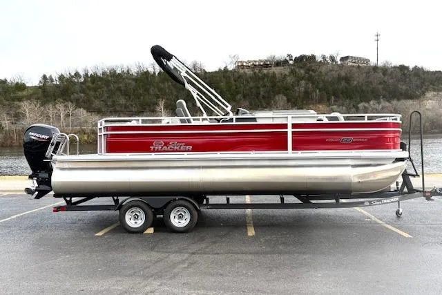 Slide: The Image of 2026 Sun Tracker Fishin' Barge 22 DLX pontoon boat on trailer, parked by a lake. - 85