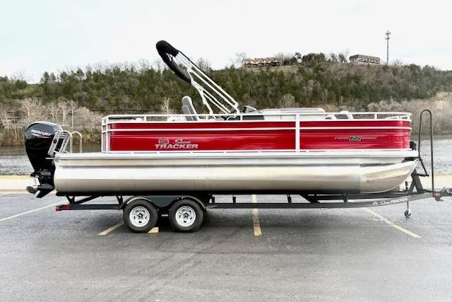 Slide: The Image of 2026 Sun Tracker Fishin' Barge 22 DLX pontoon boat on trailer by a lake. - 86