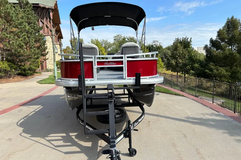 Slide: The Image of 2026 Sun Tracker Bass Buggy 18 DLX pontoon boat on trailer, parked outdoors. - 2