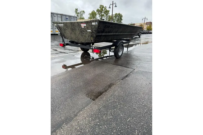 Slide: The Image of 2026 Tracker Grizzly 1648 Utility boat on trailer in wet parking lot. - 2