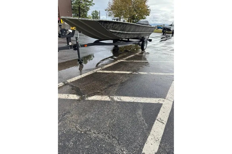 Slide: The Image of 2026 Tracker Grizzly 1648 Utility boat on trailer in wet parking lot. - 6