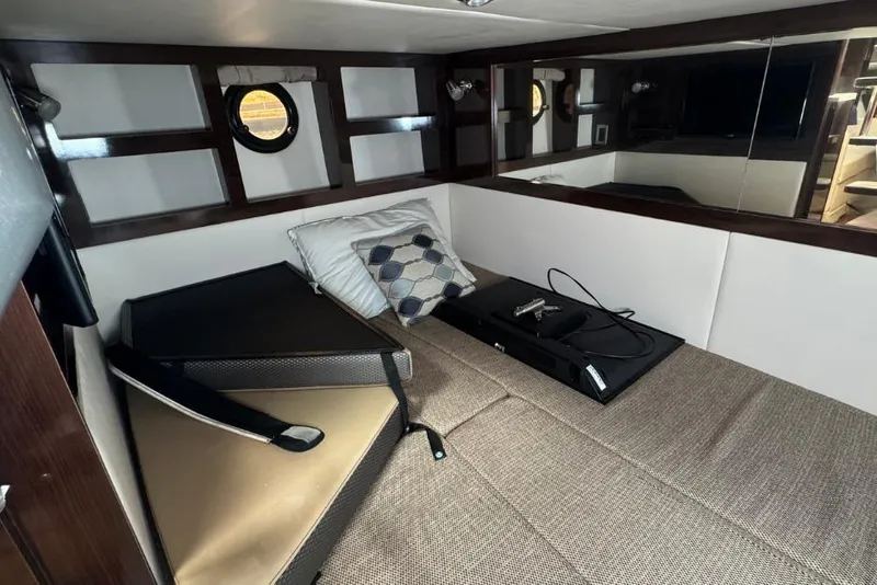 Slide: The Image of 2016 Sea Ray 350 Sundancer cabin interior with bed, pillows, and porthole window. - 53