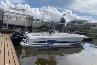 The Image of 1997 Baja 28 Sportfish boat docked on calm water under a cloudy sky. - 0