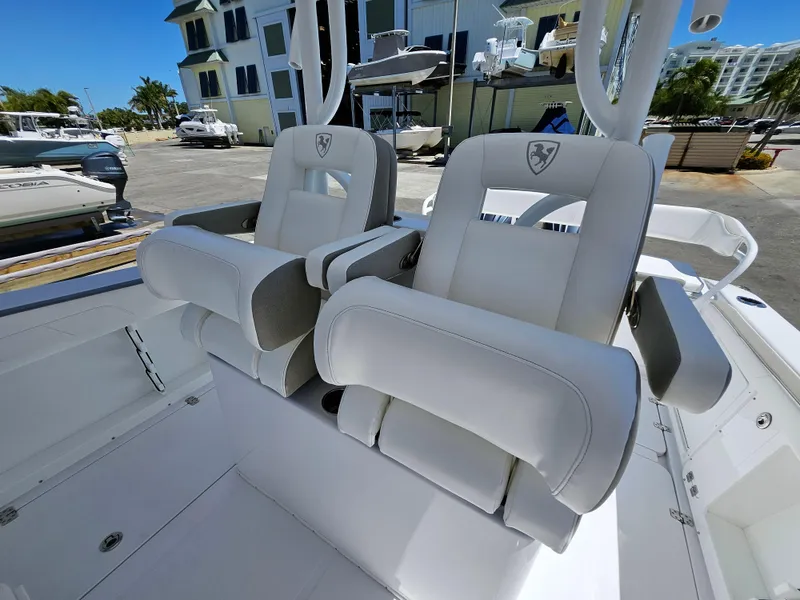Slide: The Image of Century 2900 Center Console 2022 boat with luxurious white seating in a marina setting. - 11
