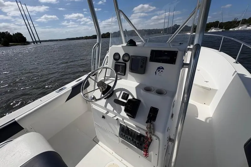 Slide: The Image of 2001 Edgewater 225CC boat cockpit with steering wheel and control panel on a sunny day. - 11