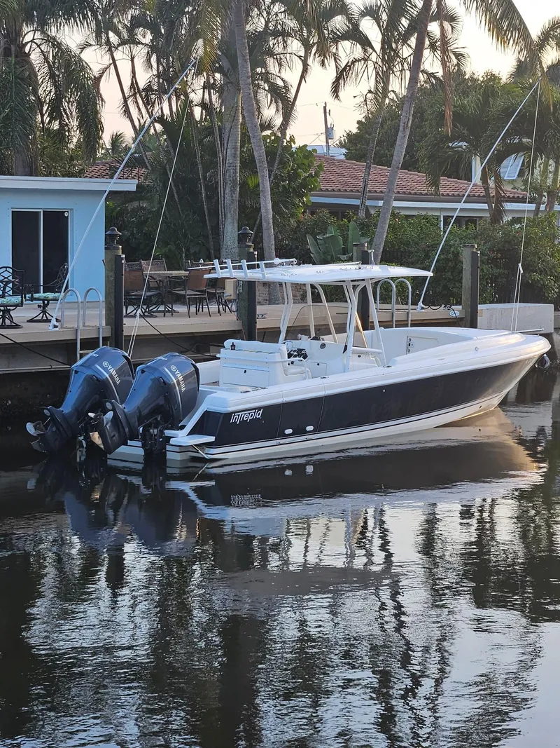 Slide: The Image of 2005 Intrepid 323 Cuddy boat docked by a waterfront home with palm trees. - 1