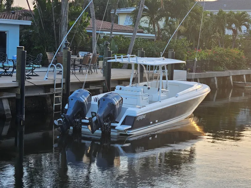 Slide: The Image of 2005 Intrepid 323 Cuddy boat docked by a waterfront home. - 2