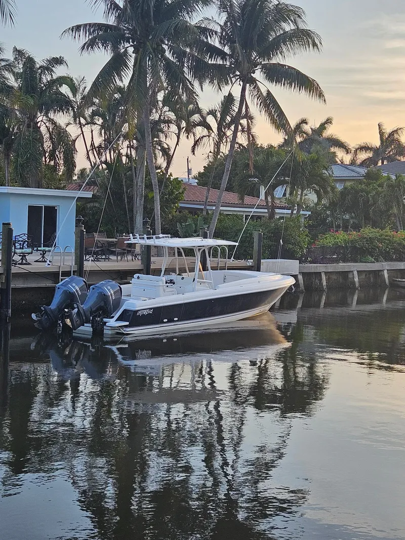 Slide: The Image of 2005 Intrepid 323 Cuddy boat docked by palm trees at sunset. - 3