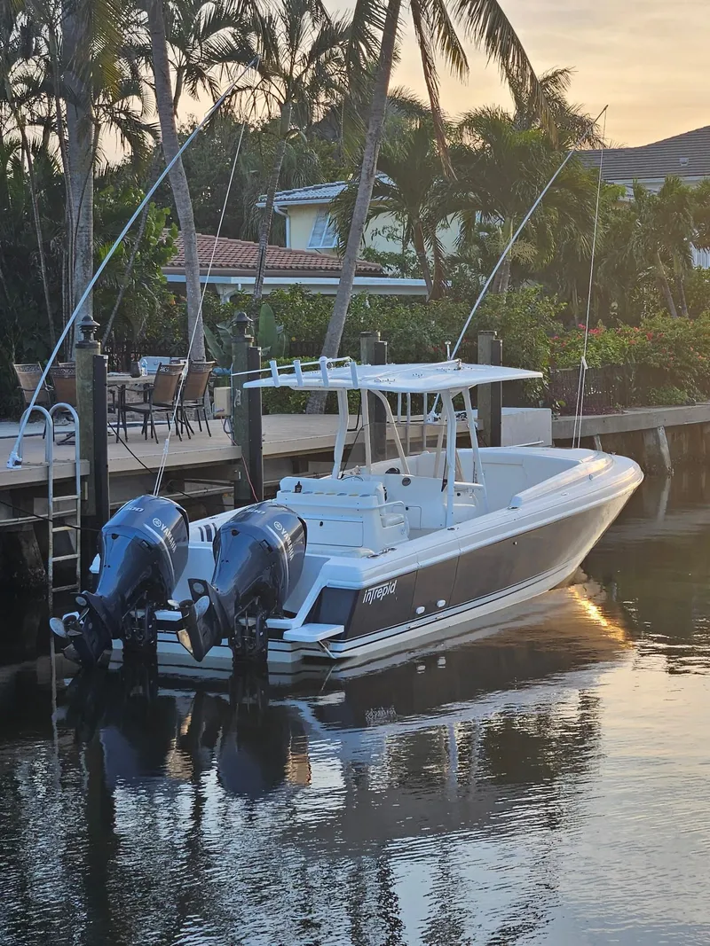 Slide: The Image of 2005 Intrepid 323 Cuddy boat docked by palm trees at sunset. - 4