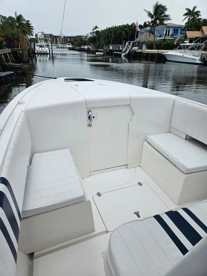 Slide: The Image of 2005 Intrepid 323 Cuddy boat interior with white seating, docked in a serene canal. - 9