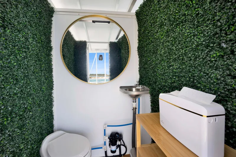 Slide: The Image of Modern bathroom with greenery walls, round mirror, and compact fixtures, A&M Manufacturing COI 2026 model. - 9