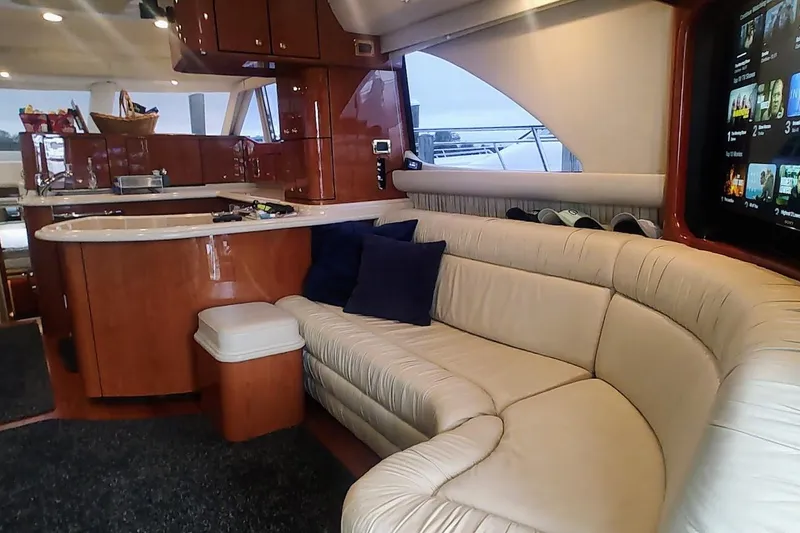 Slide: The Image of 2001 Sea Ray 560 Sedan Bridge yacht deck with seating, table, and American flag. - 14