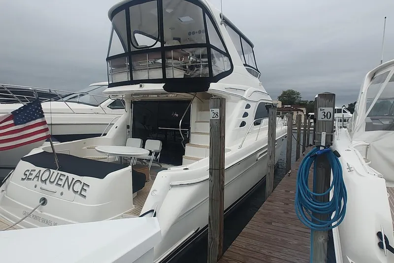 Slide: The Image of 2001 Sea Ray 560 Sedan Bridge yacht anchored near rocky shoreline with jet skis. - 4