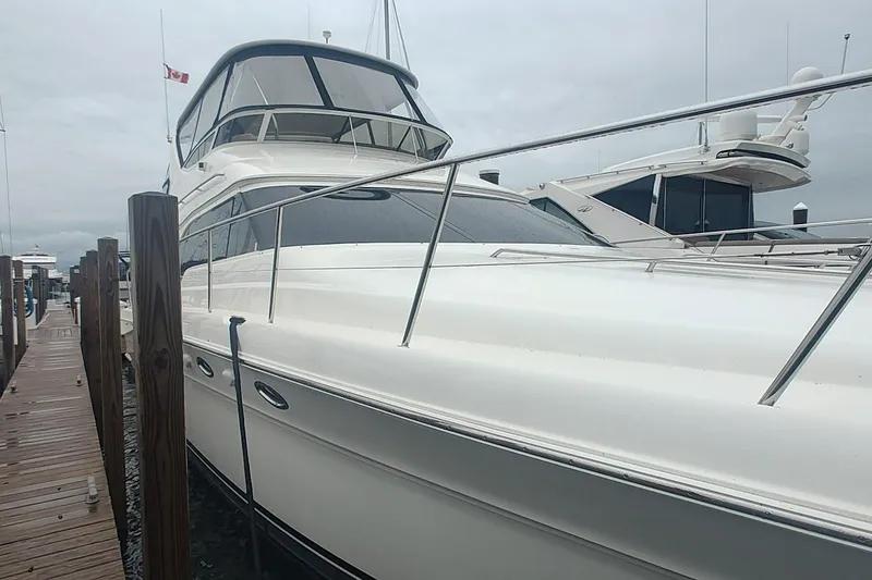 Slide: The Image of 2001 Sea Ray 560 Sedan Bridge yacht docked at marina under clear blue sky. - 6