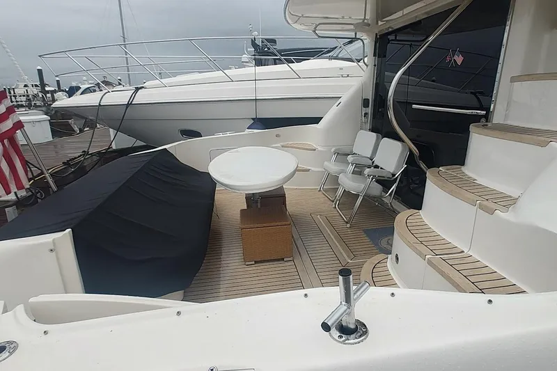 Slide: The Image of 2001 Sea Ray 560 Sedan Bridge yacht docked, featuring spacious deck and American flag. - 8