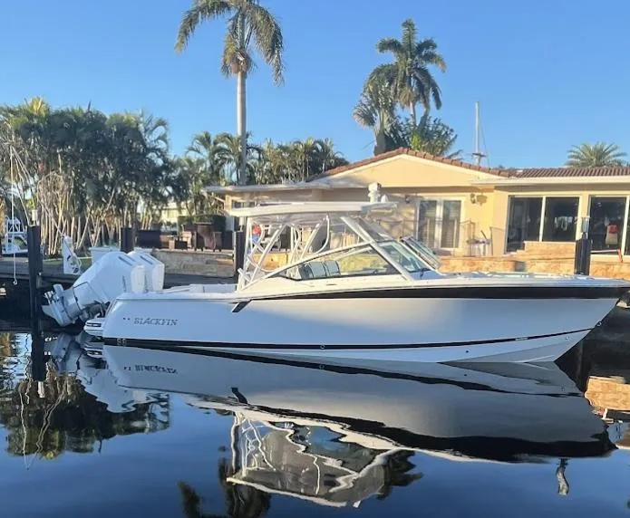 Slide: The Image of 2023 Blackfin 302 DC boat docked by a waterfront home with palm trees. - 0