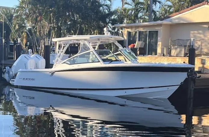 Slide: The Image of 2023 Blackfin 302 DC boat docked by a waterfront house. - 1