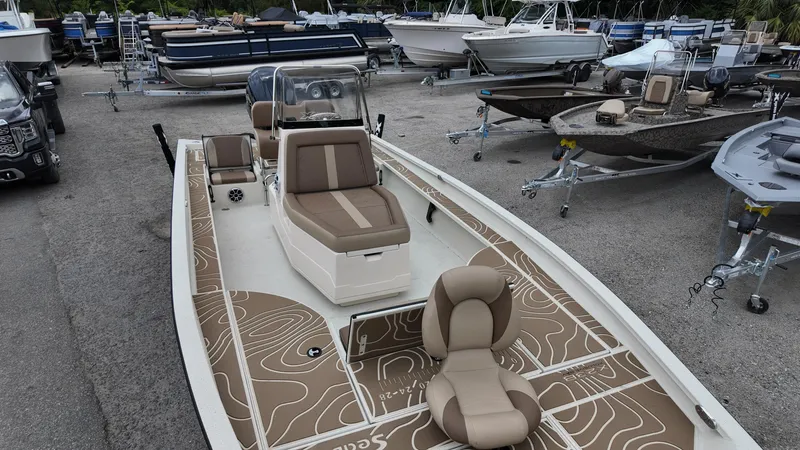 Slide: The Image of 2025 Xpress X23B Lounge boat with brown seating, parked among other boats. - 13
