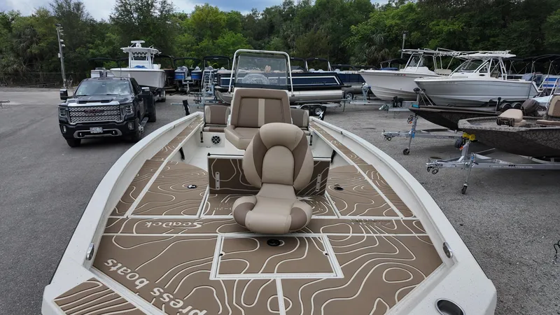 Slide: The Image of 2025 Xpress X23B Lounge boat with stylish seating, parked in a marina. - 14