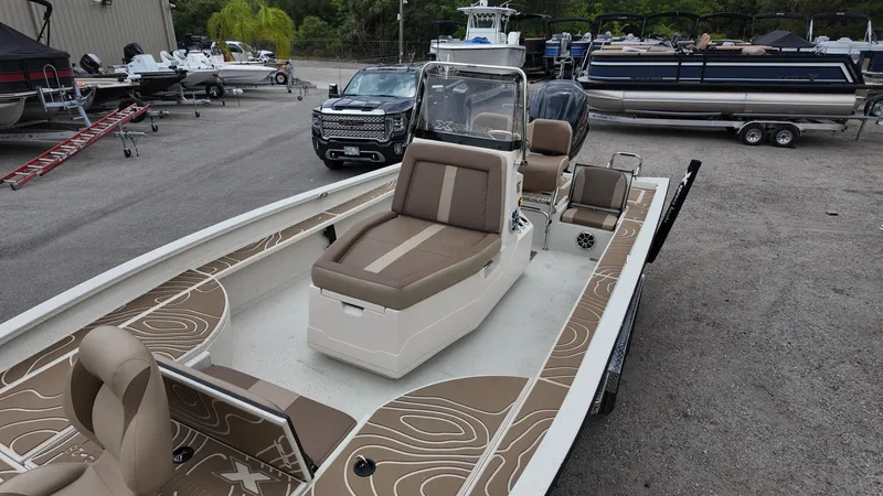 Slide: The Image of 2025 Xpress X23B Lounge boat with brown seating, parked in a marina. - 15