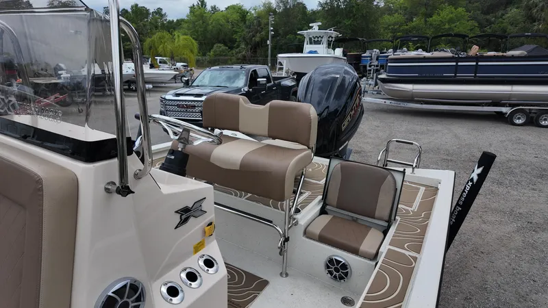 Slide: The Image of 2025 Xpress X23B Lounge boat with seating, parked in a marina with other boats. - 17