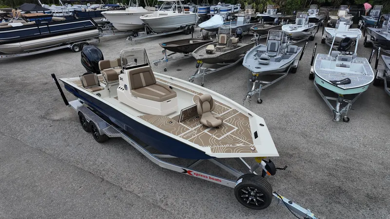 Slide: The Image of 2025 Xpress X23B Lounge boat on trailer, surrounded by various boats in a lot. - 3