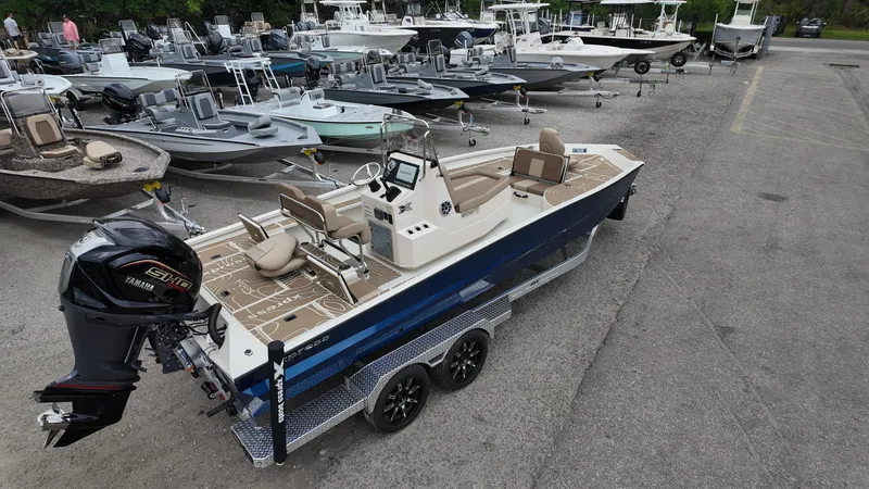Slide: The Image of 2025 Xpress X23B Lounge boat on trailer, surrounded by other boats in a lot. - 5