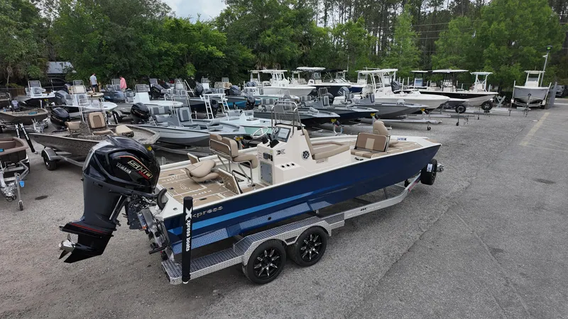 Slide: The Image of 2025 Xpress X23B Lounge boat on trailer in marina parking lot. - 6