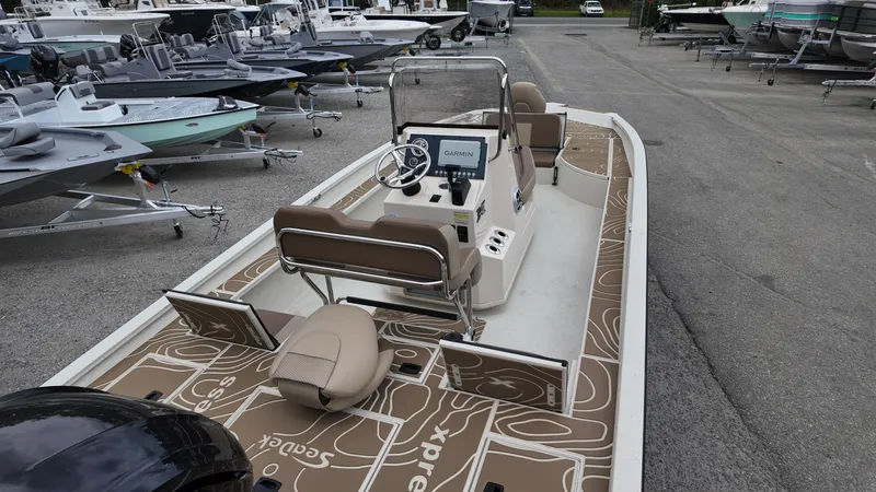 Slide: The Image of 2025 Xpress X23B Lounge boat with modern seating and navigation, parked among other boats. - 7