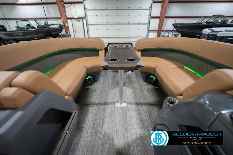 Slide: The Image of 2026 Bennington 22 MFB boat interior with tan seating and modern table in showroom. - 21