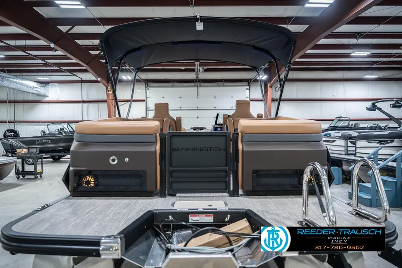 Slide: The Image of 2026 Bennington 22 MFB pontoon boat in showroom, featuring tan seating and black canopy. - 9