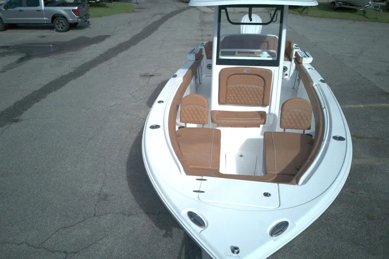 Slide: The Image of 2026 Sea Hunt Ultra 255 SE boat with tan seating, parked on pavement. - 10