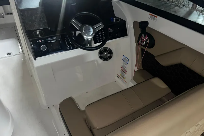 Slide: The Image of 2019 Sea Ray SDX 290 helm with steering wheel, controls, and beige seating. - 16