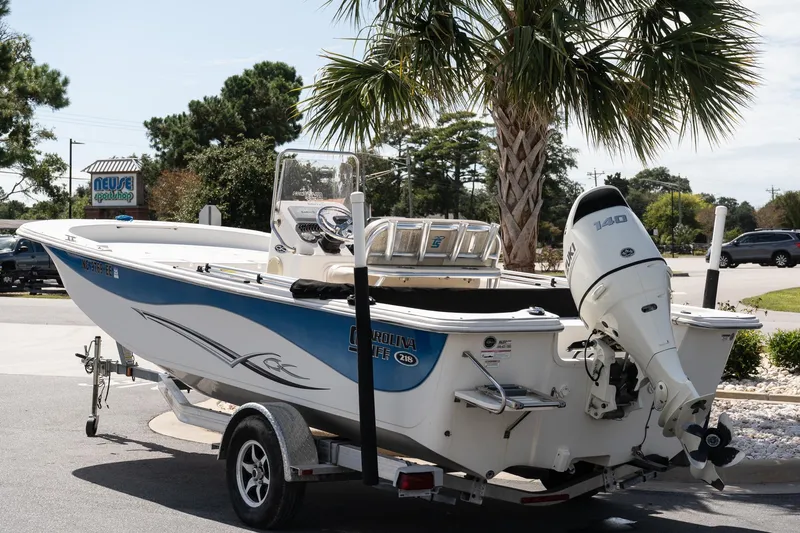 Slide: The Image of 2017 Carolina Skiff 218 DLV boat on trailer, parked near palm tree. - 5