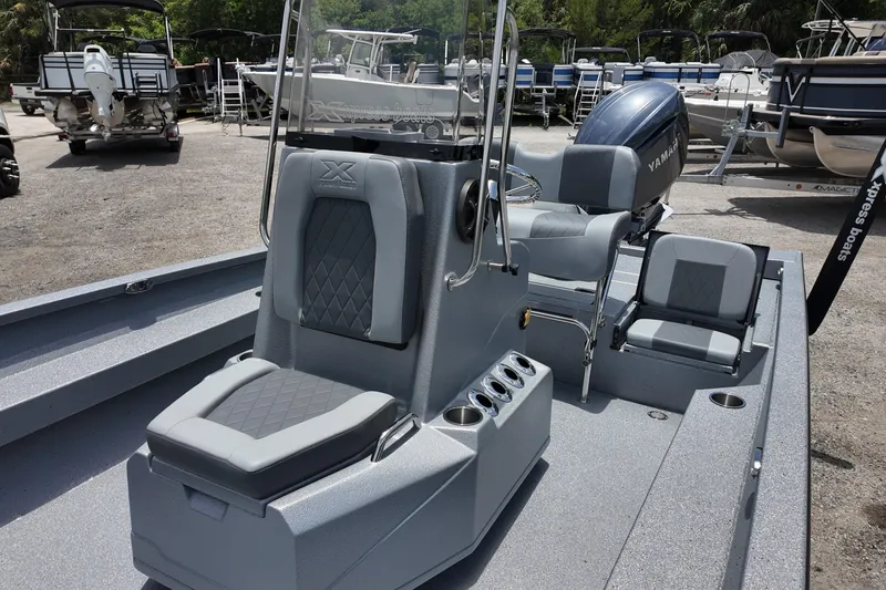 Slide: The Image of 2026 Xpress H22B Bay boat interior with seating and Yamaha engine in a marina. - 12