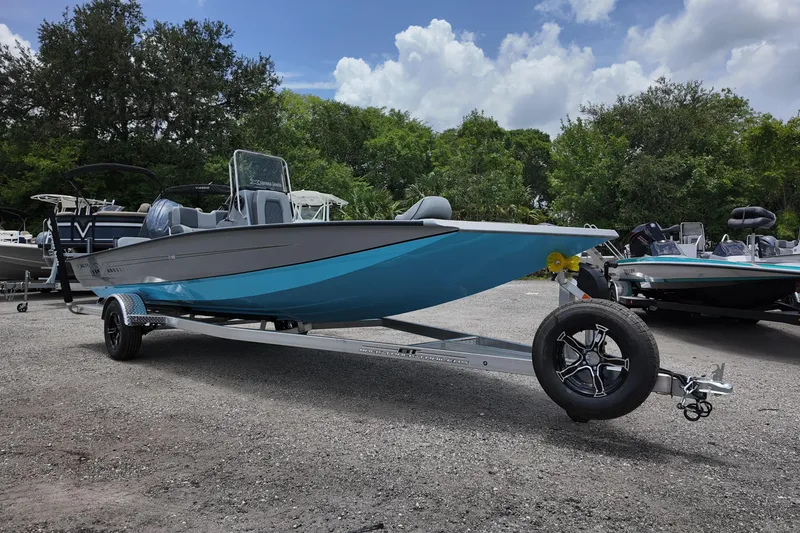 Slide: The Image of 2026 Xpress H22B Bay boat on trailer, parked outdoors with trees in background. - 2