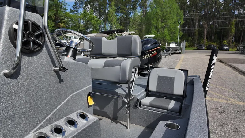 Slide: The Image of 2026 Xpress H20B boat interior with seating and steering wheel, parked outdoors. - 7