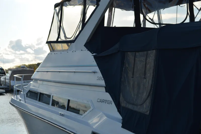 Slide: The Image of 1995 Carver 380 Santego yacht docked, featuring sleek design and covered upper deck. - 2