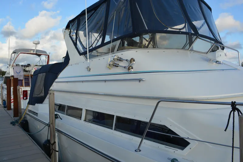 Slide: The Image of 1995 Carver 380 Santego yacht docked, featuring blue canopy and sleek white design. - 3