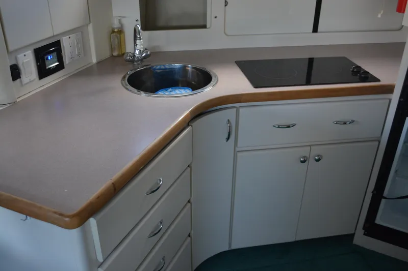Slide: The Image of 1995 Carver 380 Santego yacht kitchen with sink, stovetop, and storage cabinets. - 39
