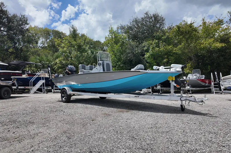 Slide: The Image of 2026 Express H20B Bay boat on trailer, parked outdoors with trees in background. - 2