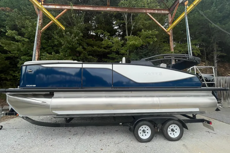 The Image of 2026 Harris Sunliner 210 pontoon boat on trailer, parked outdoors. - 0