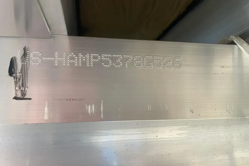 Slide: The Image of 2026 Harris Sunliner 210 hull identification number on metal surface. - 23