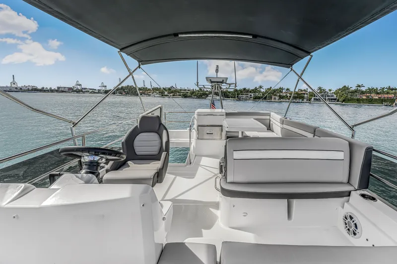 Slide: The Image of 2025 Jeanneau NC 1295 Flybridge with modern seating and scenic waterfront view. - 16