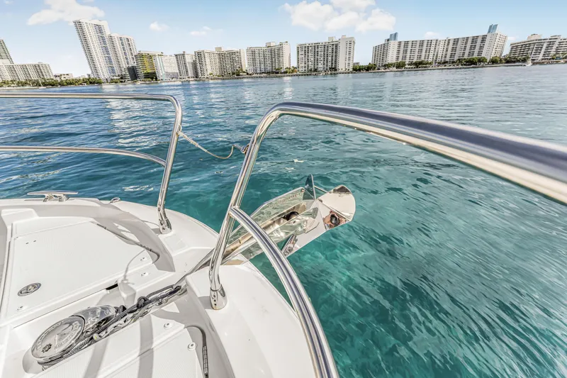 Slide: The Image of 2025 Jeanneau NC 1295 Fly yacht on clear water with city skyline backdrop. - 19
