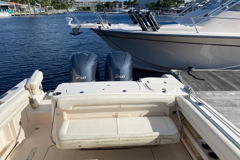 Slide: The Image of 2015 Grady-White Freedom 285 boat interior with seating, docked by palm trees. - 18
